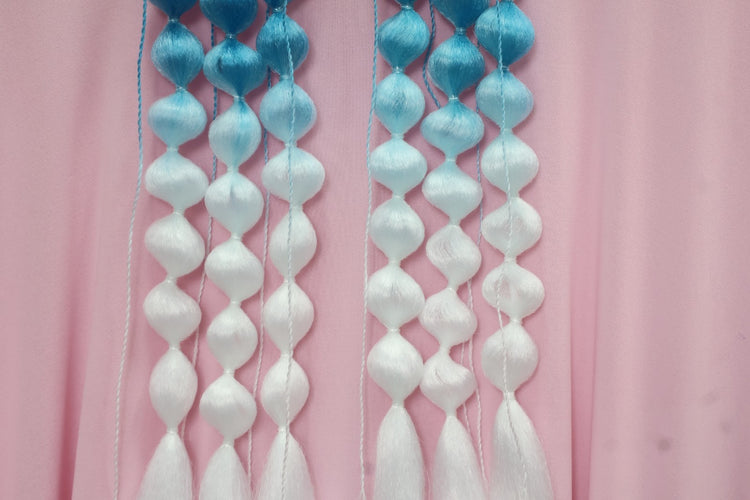Decorative string with blue and white beads against a pink background