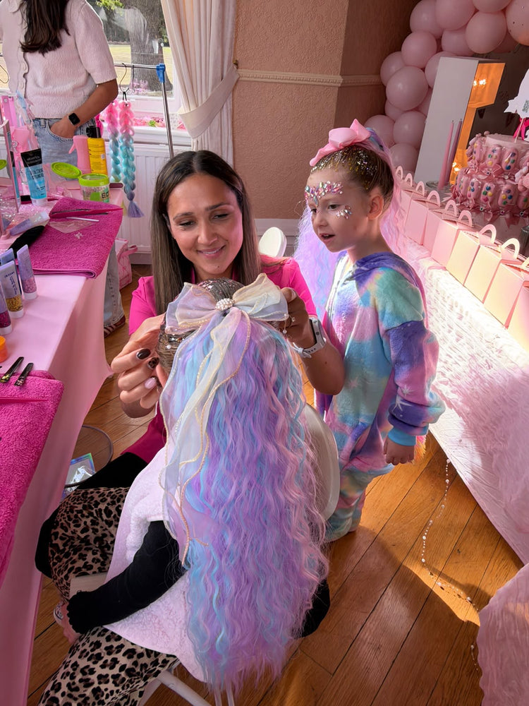 Glitter Braid Bar stylist adding a pastel mermaid hair extension and bow at a kids birthday party