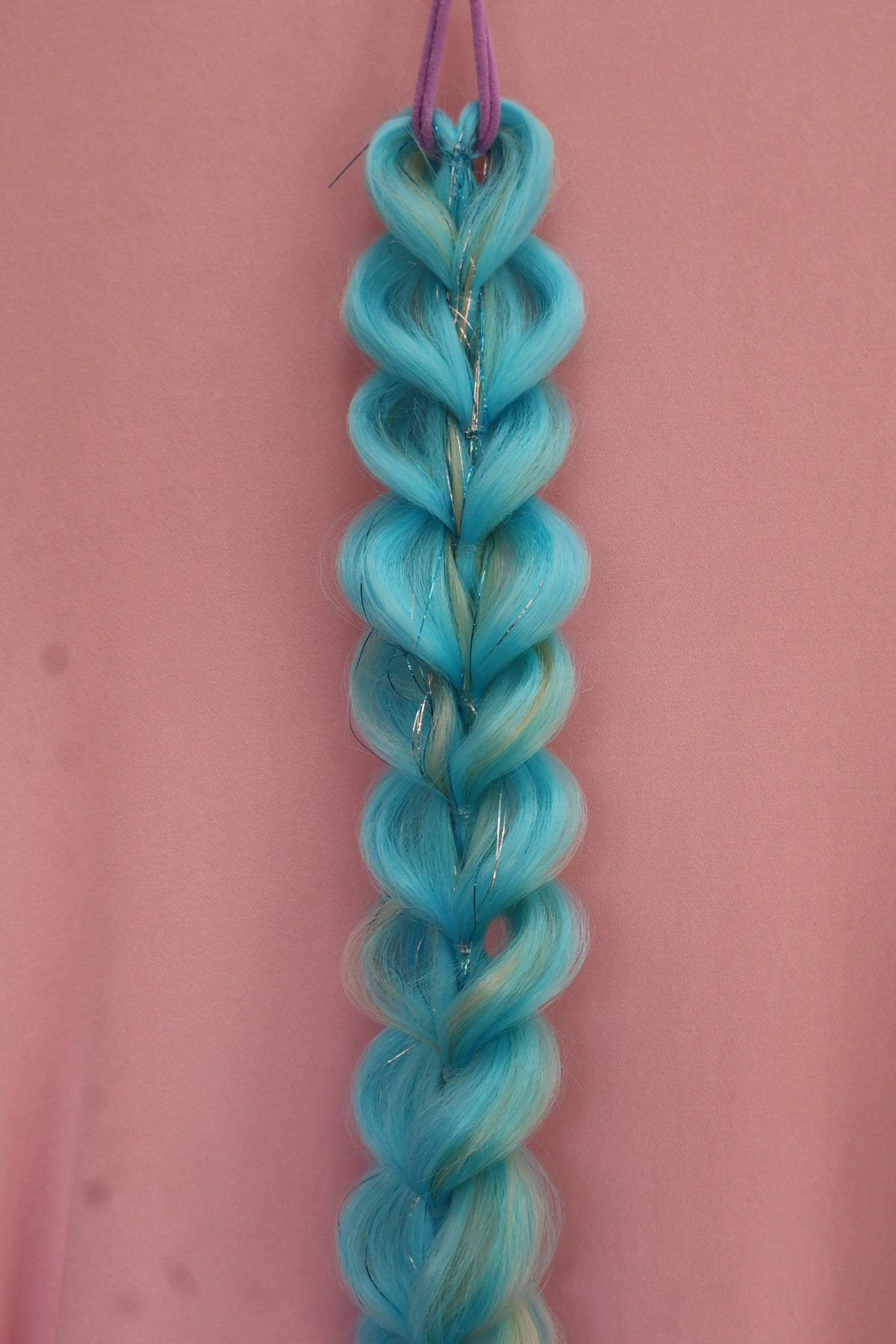 Braided blue hair extensions on a pink background
