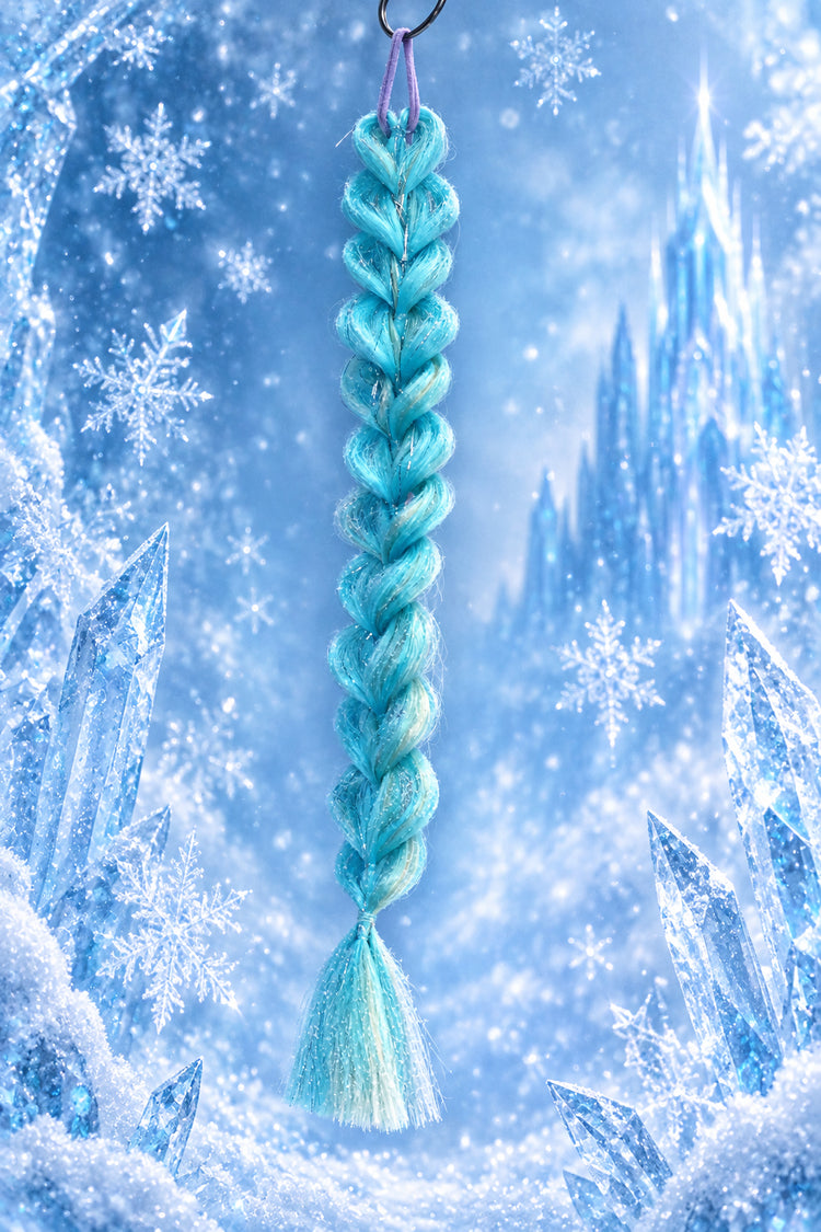 A braided faux hair accessory in light blue and mint green hangs from a black ring against a digital icy winter background with snowflakes and ice crystals.