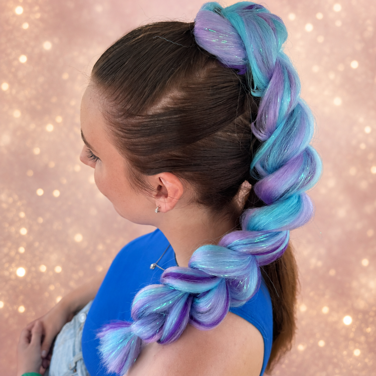 Girl wearing a blue and purple Jumbo Dragon Hair Braid against a blush and gold glitter backdrop